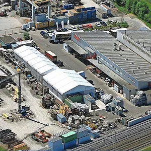 Luftaufnahme eines Werkgeländes mit mehreren Hallen und Abstellflächen. Davor Bahngleise